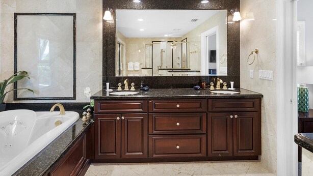 A bathroom with a large mirror, two sinks, a bathtub, and dark wooden cabinets. - Southern Comfor t (Key West)