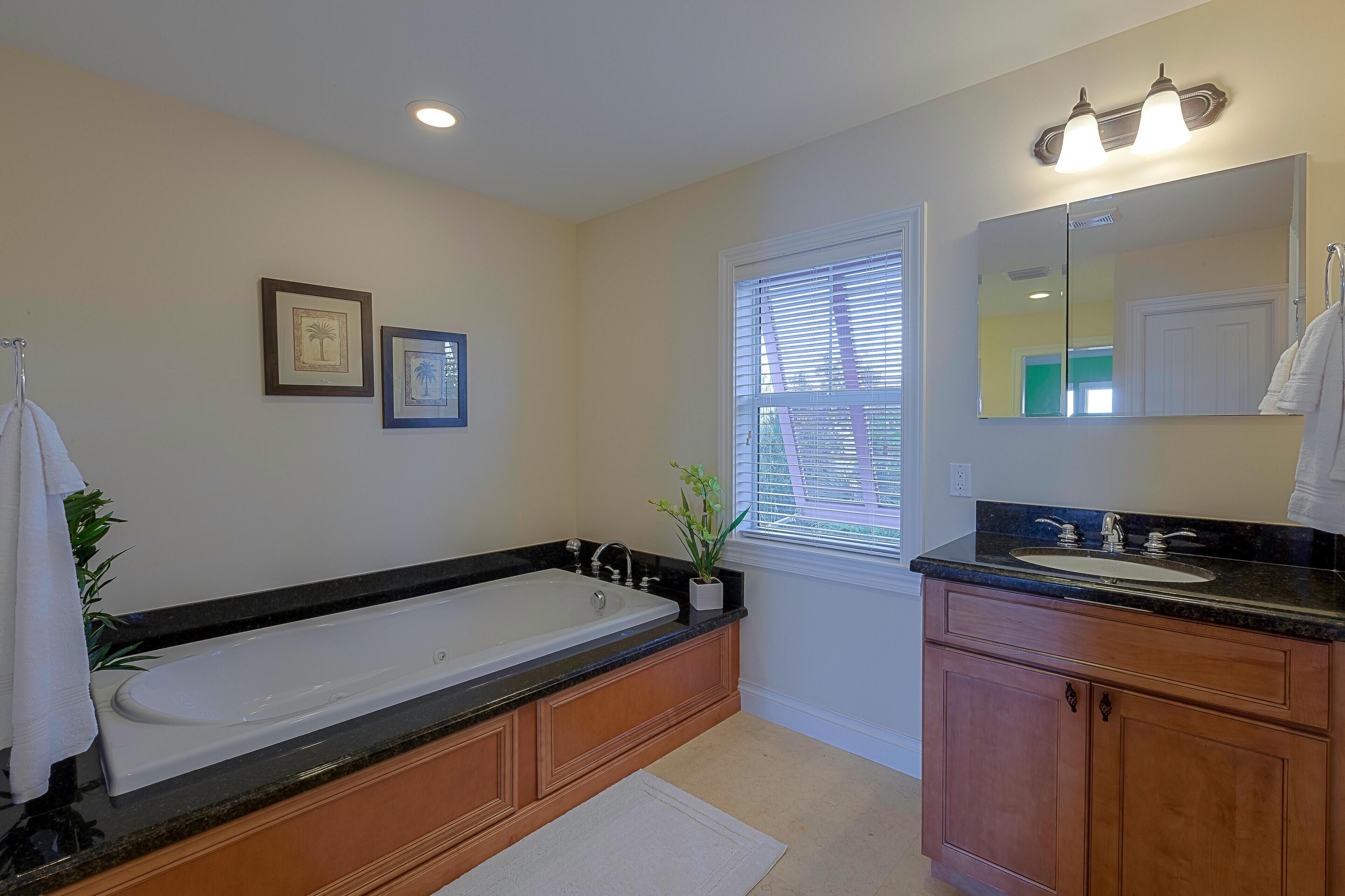 A modern bathroom with a large bathtub, a sink, and a vanity with cabinets.