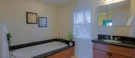 A modern bathroom with a large bathtub, a sink, and a vanity with cabinets.