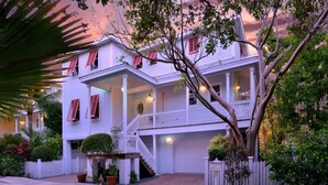 A two-story white house with a balcony, a covered front porch, and a garage. - Seaside Retreat (Key West)