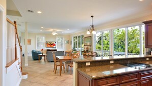 A spacious kitchen with a granite countertop, wooden cabinets, and a dining area with a table and chairs. - Seaside Retreat (Key West)