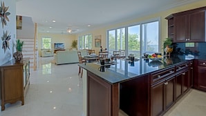 A spacious kitchen with a large island, wooden cabinets, and a dining area with chairs and a table. - Coastal Comfor t (Key West)