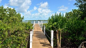 A wooden pier leading to a body of water, surrounded by dense greenery. - Coastal Comfor t (Key West)