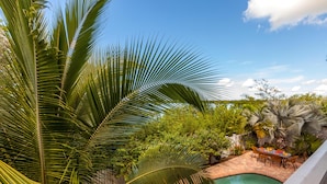 A swimming pool surrounded by lush greenery and a patio area with outdoor furniture. - Coastal Comfor t (Key West)