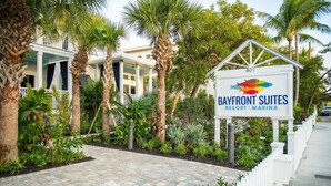 Schild für Bayfront Suites Resort & Marina, ein Weg, gesäumt von Palmen, mit einem weißen Zaun.