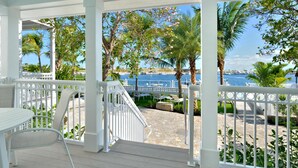 A covered outdoor area with white railings, a wooden deck, and a view of the marina and water. - Bayview Middle (Key West)