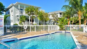 A swimming pool with a 5 ft depth marker, surrounded by a white fence and palm trees. - Sunset North (Key West)