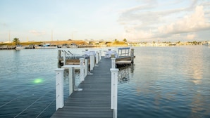 A wooden dock leading to a marina with boats and a cityscape in the background. - Sunset North (Key West)