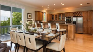 A spacious kitchen with wooden cabinets, a stainless steel refrigerator, and a dining area with a table set for six. - Paris Mango (Key West)