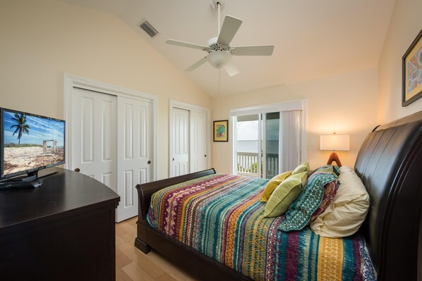A bedroom with a bed, a ceiling fan, a television, and a balcony door. - Paris Mango (Key West)