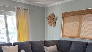 Un salon moderne avec un canapé d’angle gris, un tapis à motifs et une décoration murale représentant des poissons.