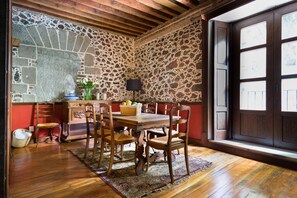 A dining area with a stone wall, wooden ceiling, and a large window. - 1BR Historic suite w/balconies - 100 mts from the Cathedral. CASA SAUTO (Ciudad de México)