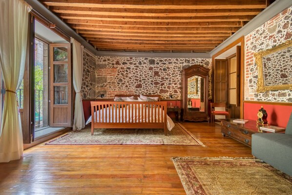 A room with a wooden bed, stone walls, and a large mirror. - 1BR Historic suite w/balconies - 100 mts from the Cathedral. CASA SAUTO (Ciudad de México)