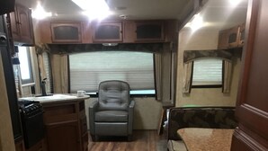 Une cuisine compacte pour camping-car, dotée de meubles en bois, d’un four à micro-ondes intégré et d’un coin salon avec un banc rembourré.