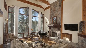 A spacious living room with a stone fireplace, large windows, and a cozy seating area.