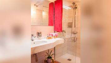 Een douche, handdoeken, zeep, toiletpapier