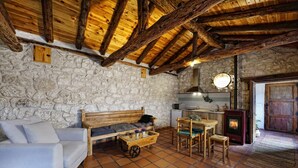 Un interior rústico con paredes de piedra, techo de madera, un sofá, una pequeña mesa y una chimenea.