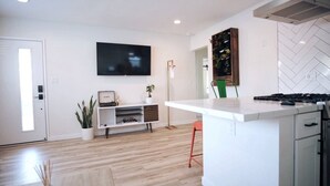 Una cocina moderna con una isla central, un televisor de pantalla plana montado en la pared y un salpicadero con motivo de espiga.