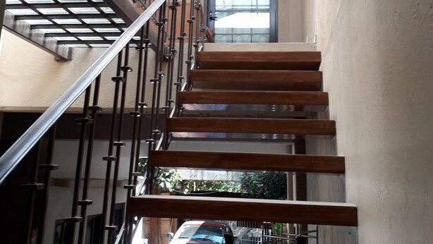 Un escalier avec des rampes en métal et des marches en bois menant à un palier.