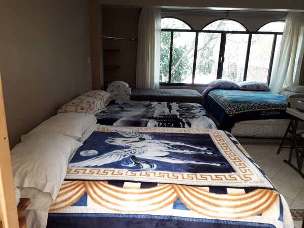 Un dormitorio con dos camas, una ventana con cortinas y un escritorio con silla.