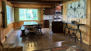 Ein Holzblockhaus-Innenraum mit Essbereich, Küche und einem großen Gemälde einer Eule an der Wand.