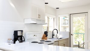 Een moderne keuken met witte kastjes, een ingebouwde kookplaat en een koffiezetapparaat.
