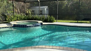 A clear swimming pool with a tiled edge, surrounded by a fence and lush greenery. - Beach / Pool Oasis in Beautiful Naples, Fl. (Naples)