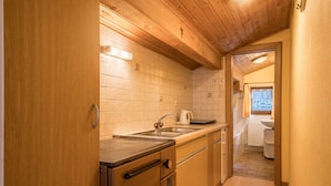 Une cuisine de taille réduite, avec des meubles de rangement en bois, un évier et une fenêtre.