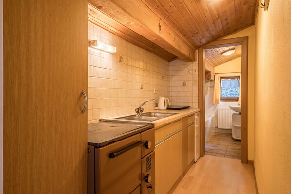 Una cucina compatta con mobili in legno, un lavello e una finestra.