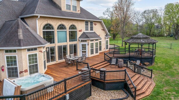 Et stort hus med terrasse, jacuzzi og en pavillon.