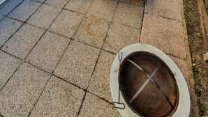 Eine Terrasse mit einem Holztisch, einer Sitzgruppe mit Auflagen und einem Metallgrill.