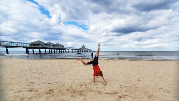 Ein Strand mit einem Pier im Hintergrund.