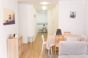 Ein Zimmer mit Esstisch, Stühlen, einer Couch, einem kleinen Beistelltisch und einem Wandbild.