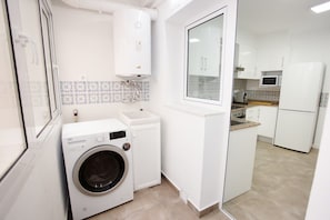 Eine kompakte Küche mit integriertem Waschmaschine, einer Mikrowelle und einem Kühlschrank.