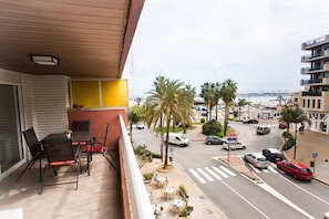 Ein Balkon mit Tisch und Stühlen, mit Blick auf eine Straße mit Autos und Palmen.