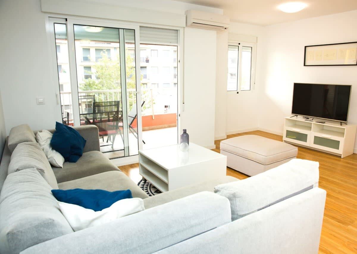 Un salon moderne comprenant un canapé, une table basse, un meuble pour la télévision et une porte-fenêtre coulissante donnant sur un espace extérieur.