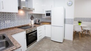 Una cocina compacta con alacenas blancas, horno empotrado, microondas y lavamanos.