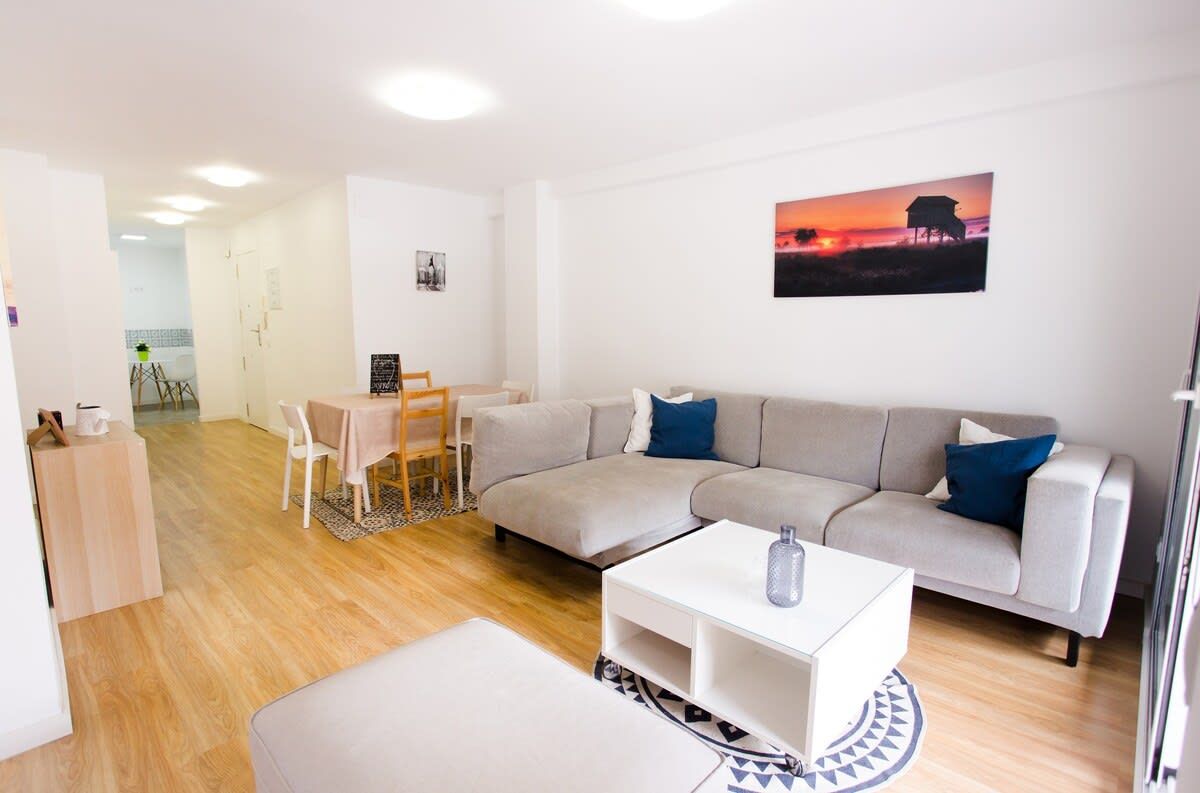 A modern living room with a sofa, a coffee table, and a dining area with chairs.