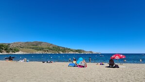 A beach with people sunbathing and swimming, a red umbrella, and boats in the water. - House with view of the sea and vineyards; Near coastal path and town center (Port-Vendres)