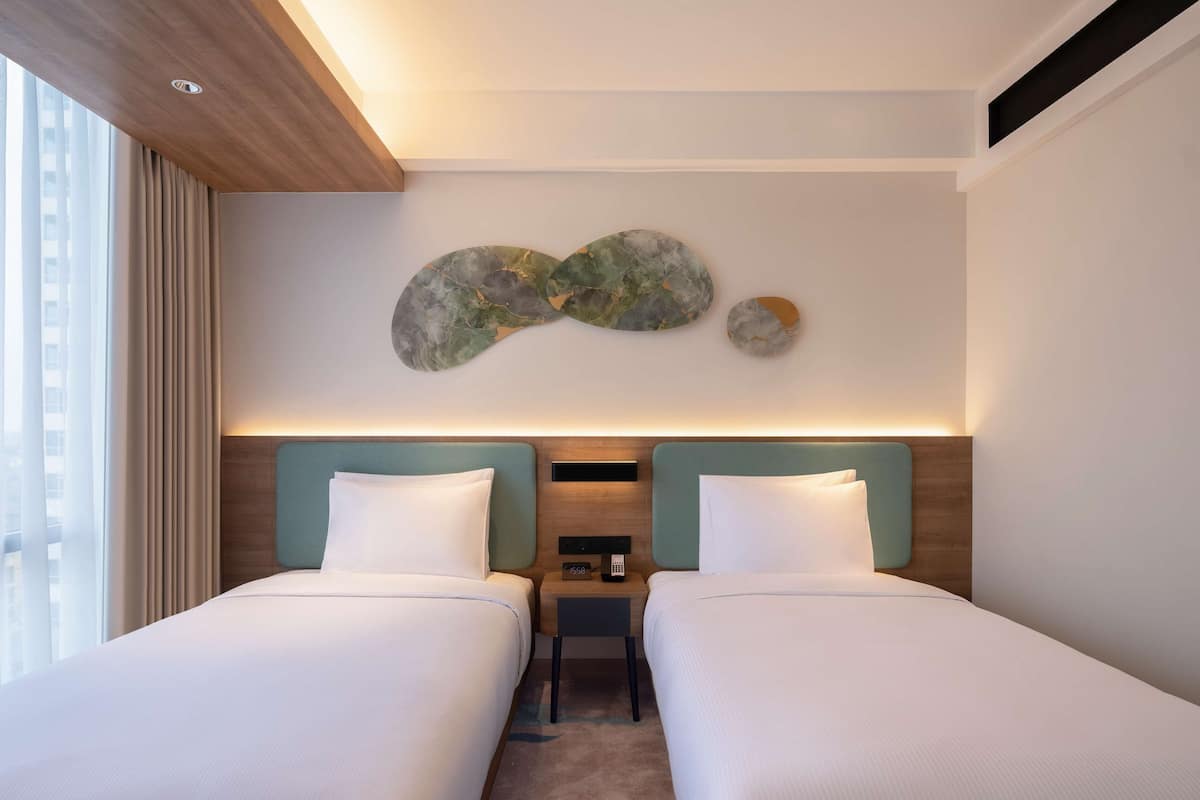Habitación de hotel con dos camas, techo de madera, decoración de pared de mármol y vista a un edificio.