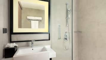 Un baño moderno con un lavabo blanco, un espejo enmarcado y una zona de ducha con mampara de cristal.