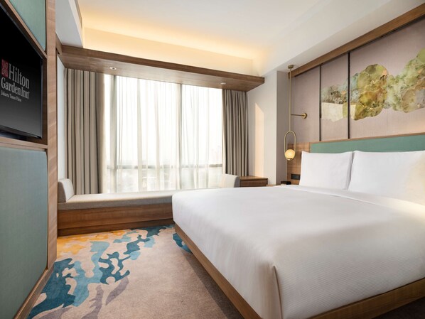 Une chambre d’hôtel dotée d’un grand lit, d’un coin salon offrant une vue sur la ville, d’un téléviseur à écran plat et d’une œuvre d’art moderne accrochée au mur.
