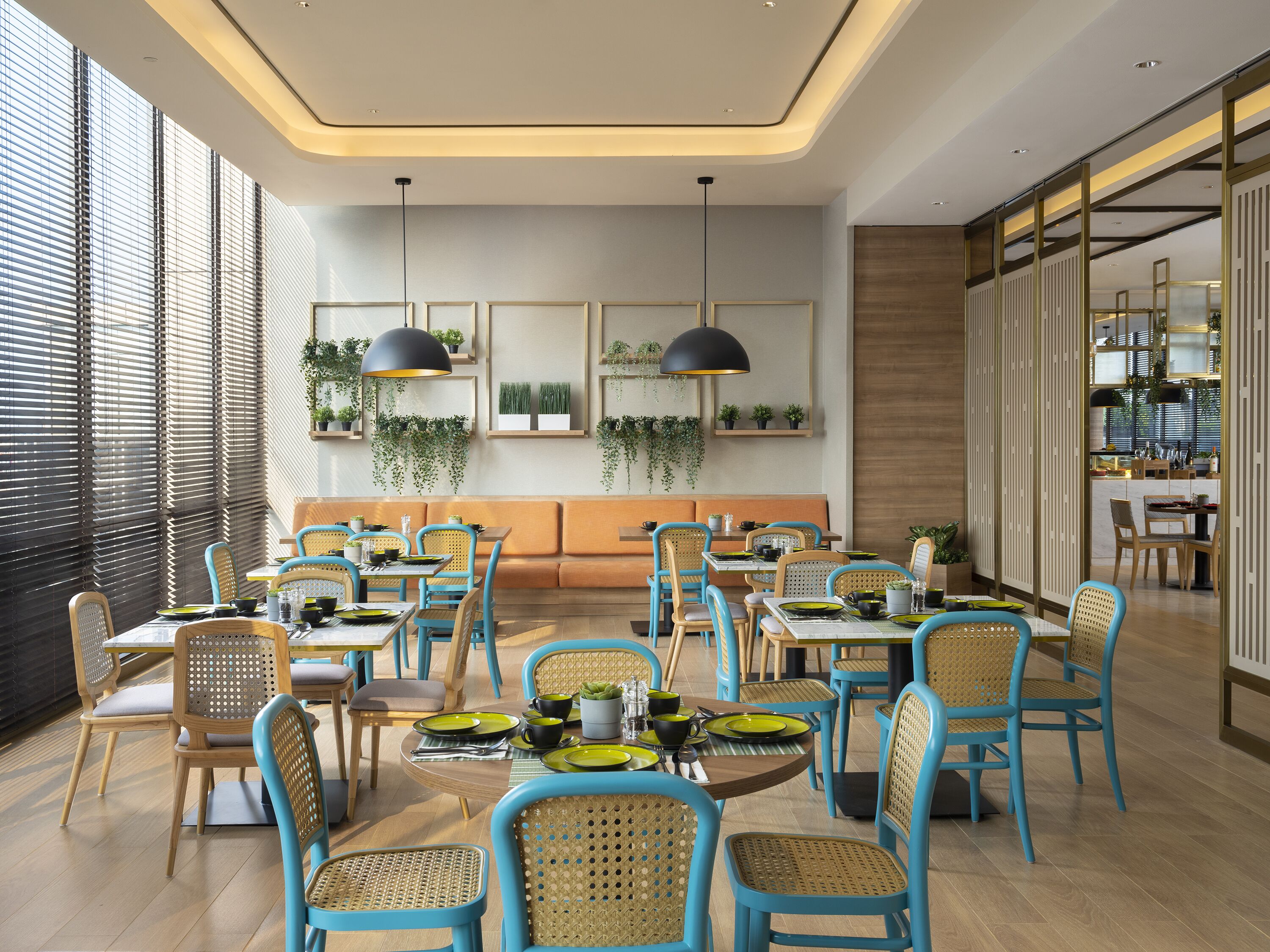 A modern dining area with blue chairs, wooden tables, and pendant lighting.