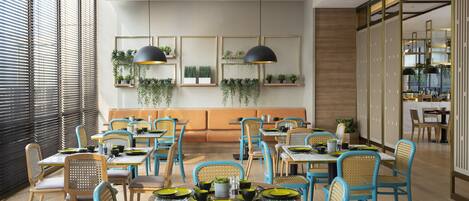 A modern dining area with blue chairs, wooden tables, and pendant lighting.