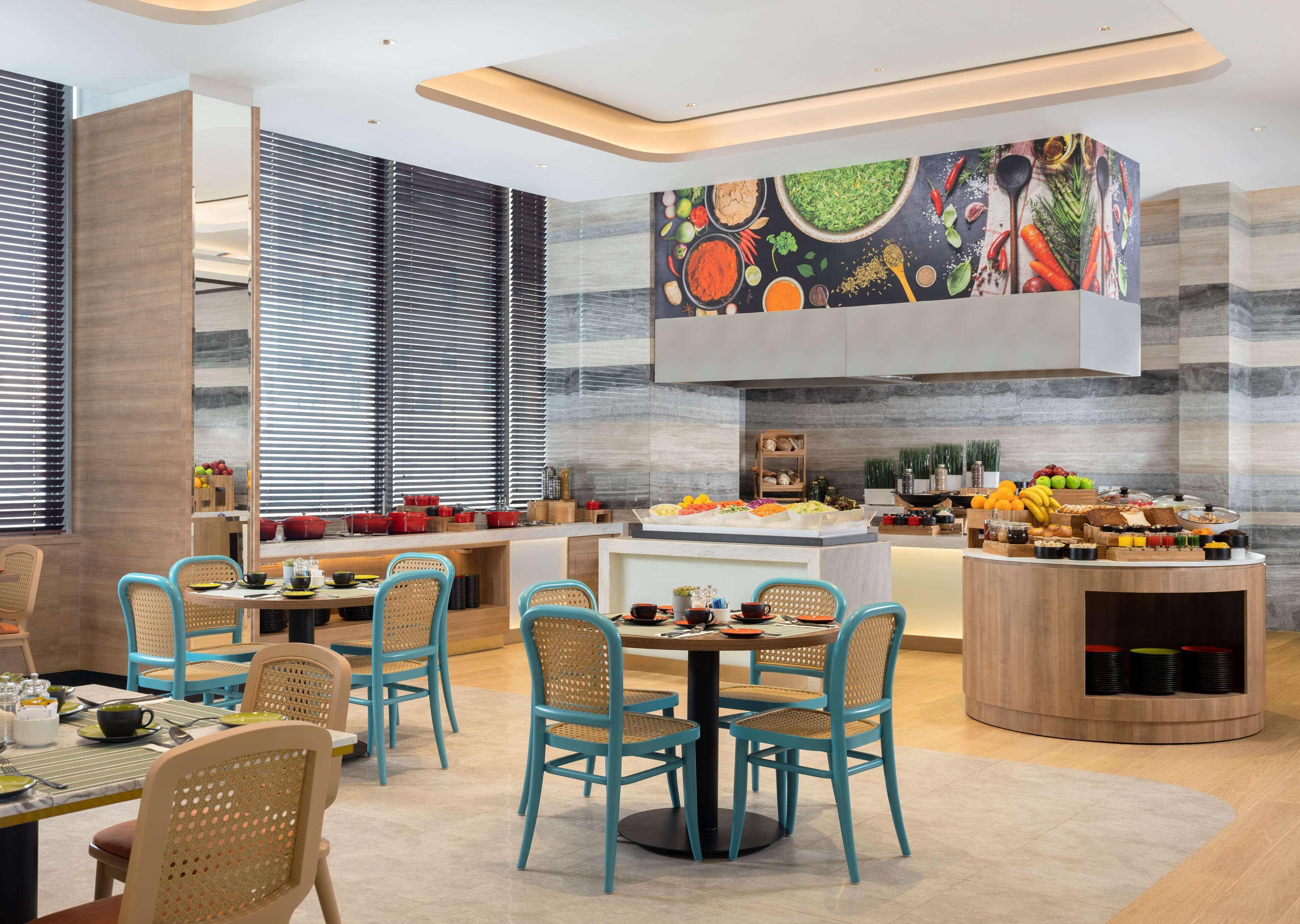 A modern dining area with a central island, blue chairs, and a variety of food items displayed on the island.