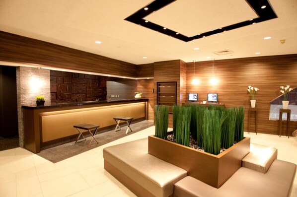 Welcome to our reception area, featuring a sleek design with a reception desk, comfortable seating, and a natural touch from the planter.