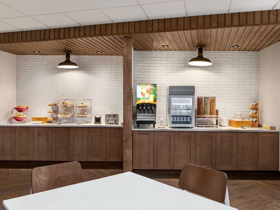 A modern kitchen with wooden cabinets, a white brick backsplash, and a coffee machine.