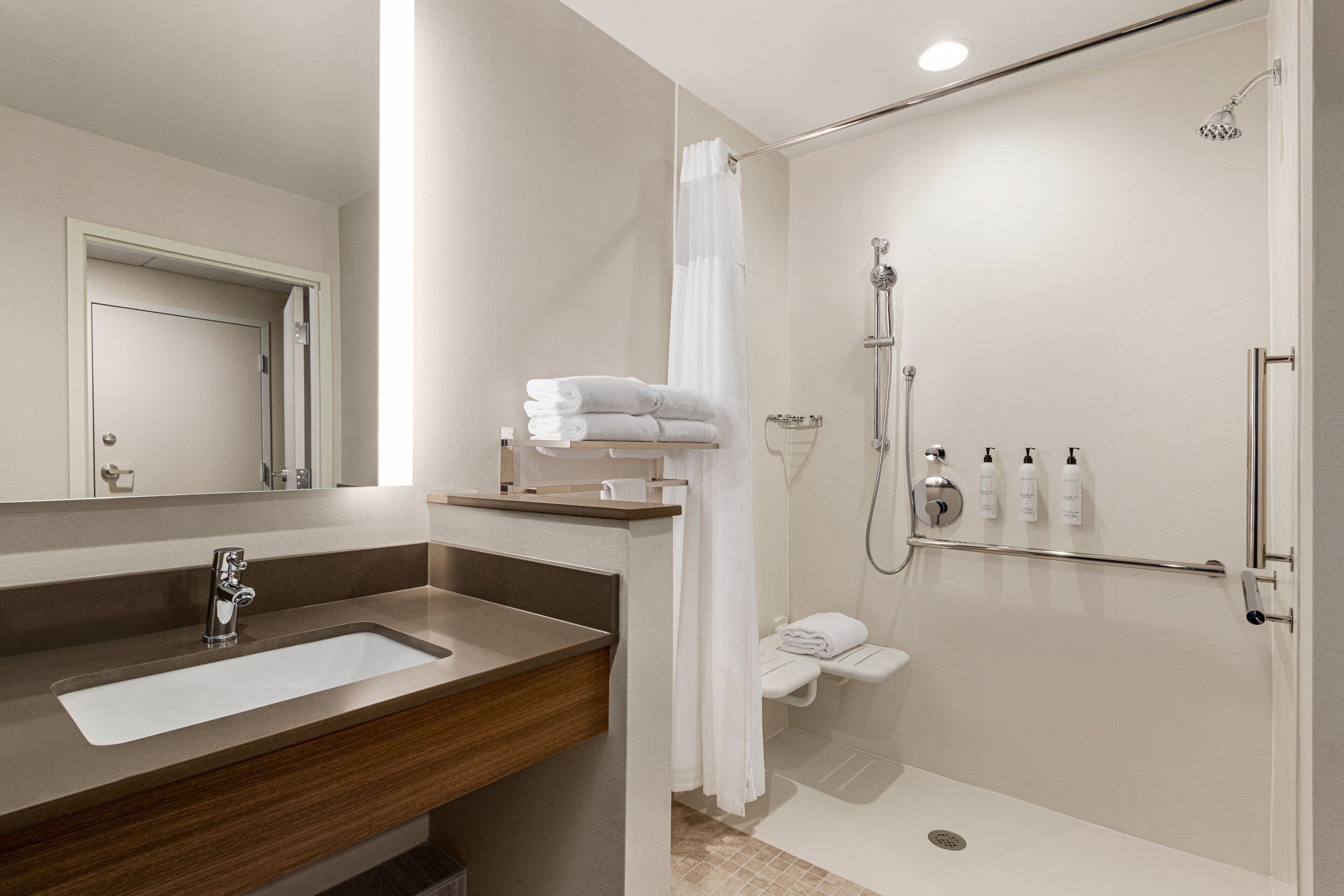 A modern bathroom with a sink, mirror, shower, and toilet.