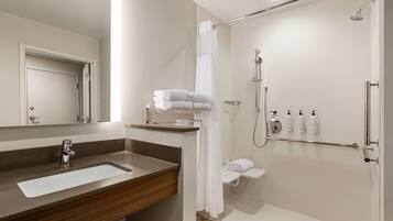A modern bathroom with a sink, mirror, shower, and toilet.