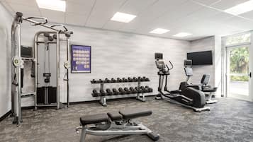 A gym with weight machines, dumbbells, a bench, and treadmills.